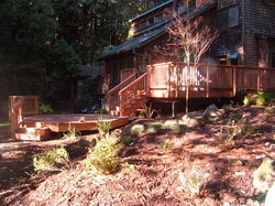 Back yard wooden deck, stairs, walkways and landscaping with rocks and shrubs.